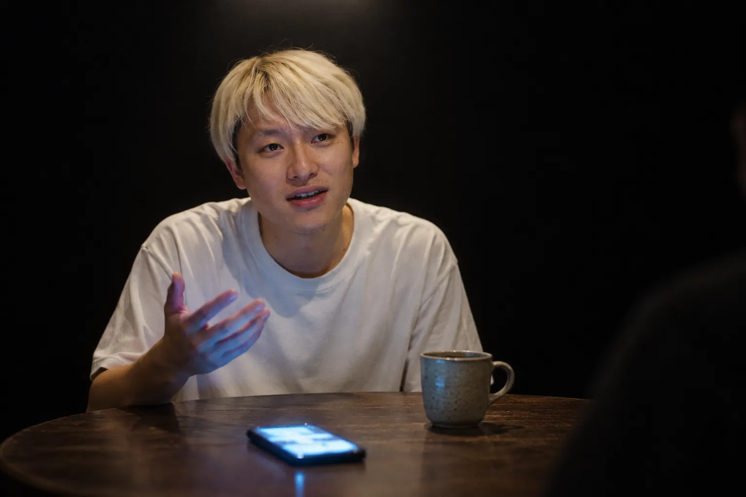 円卓で話すがく。手元のスマホが青く光っている